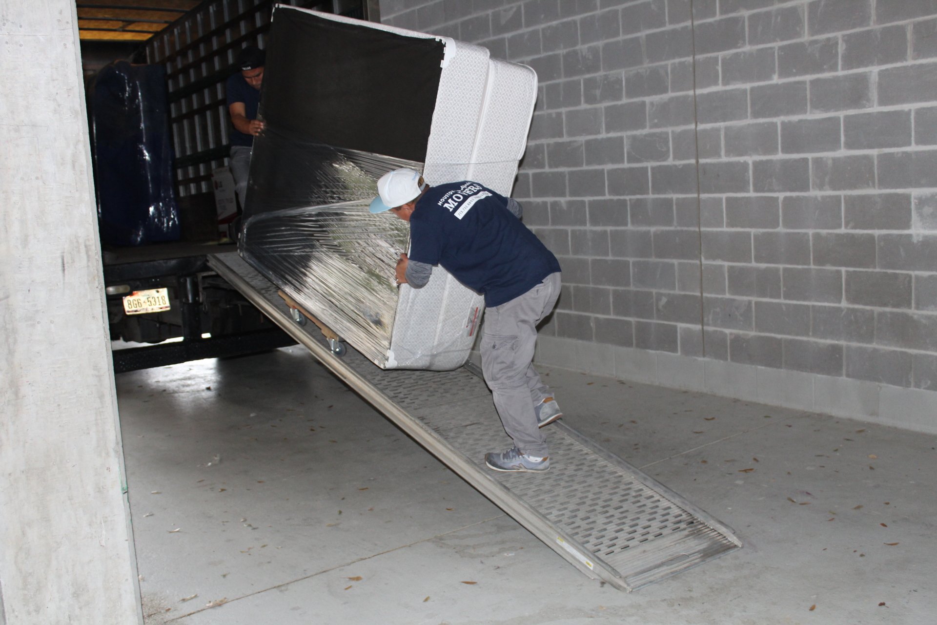 Movers Pushing Mattress Up Ramp